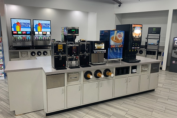 Sample of a straight retail counter featuring integrated cup holders, condiment stations, trash and napkin dispensers, storage cabinets.