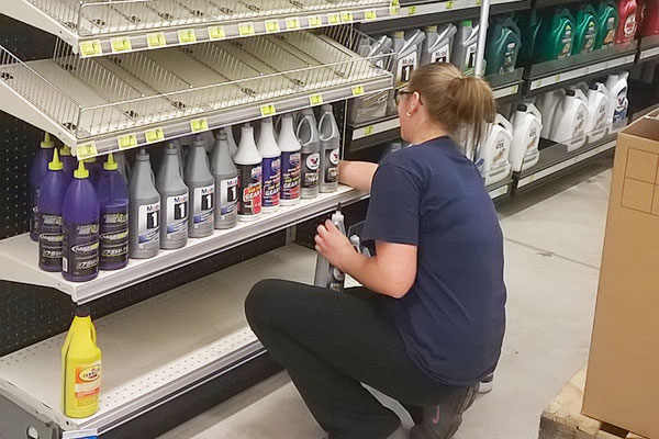 A DisplayMax team member arranging product on a newly installed Lozier retail fixture