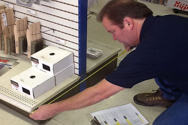 A DisplayMax team member, measuring retail fixtures for a commercial store survey