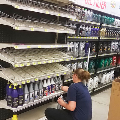 A DisplayMax team member arranging product on a newly installed Lozier retail fixture