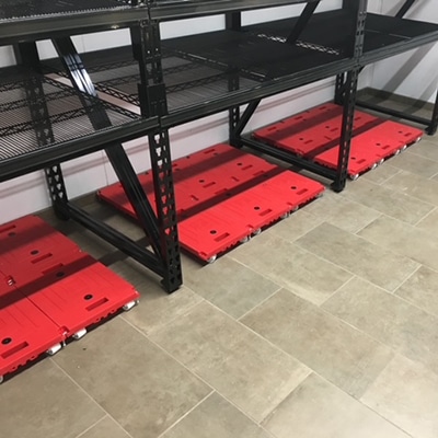 Black metal retail shelving units installed over red rolling base platforms on a tiled floor, designed and installed by DisplayMax team